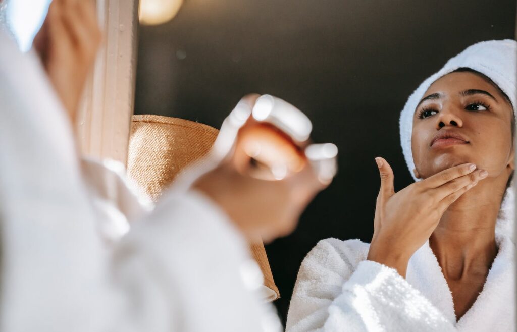 Black women applying cream on face. 