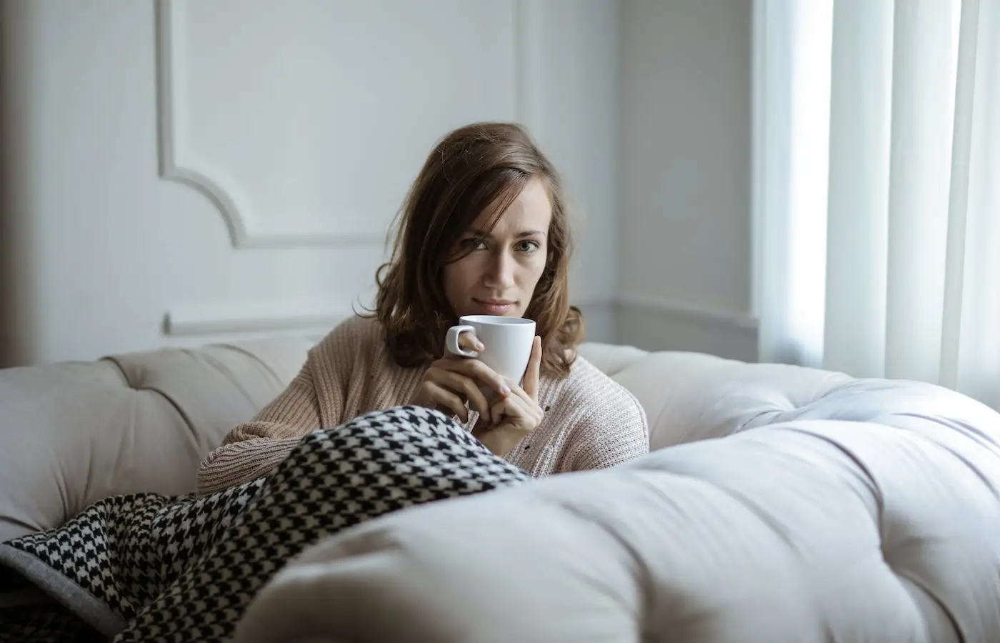 woman drinking coffee on sofa - selfcare ideas for moms