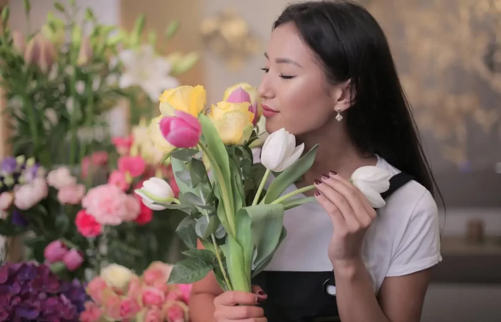 woman smelling bouquet of flowers - self-care ideas for moms