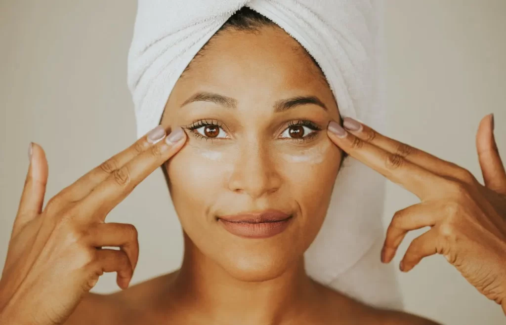 A black woman putting on face cream. - Anti-Aging Skincare Routine