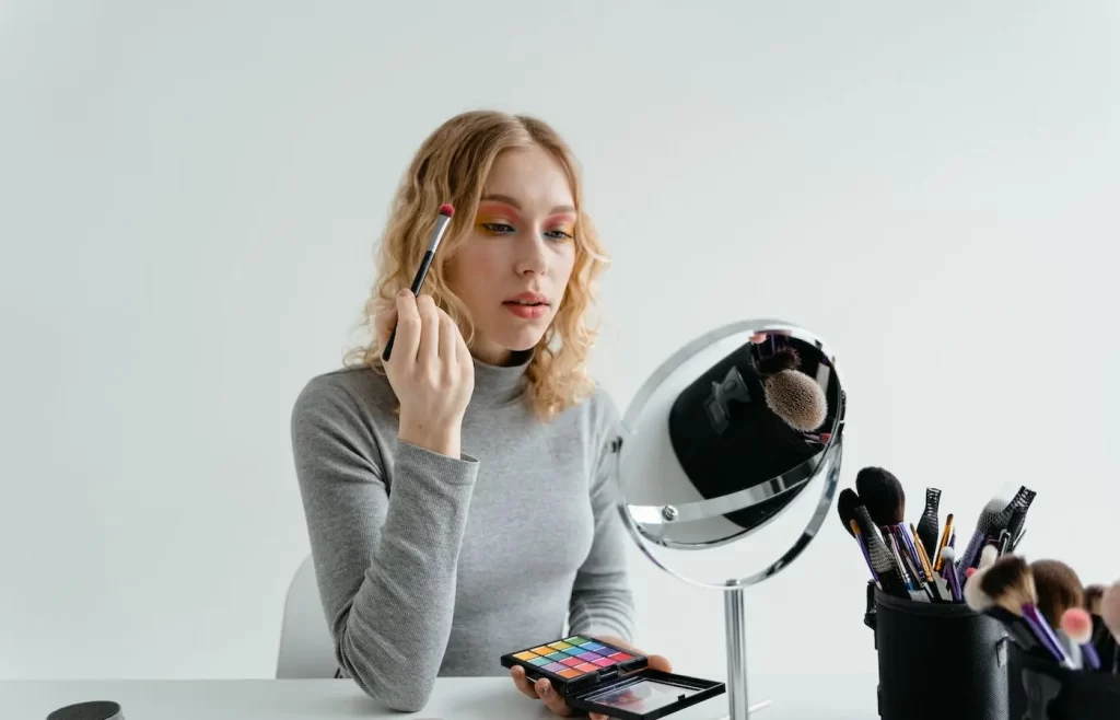 Blond woman putting on eyeshadow. - must have eye makeup brushes