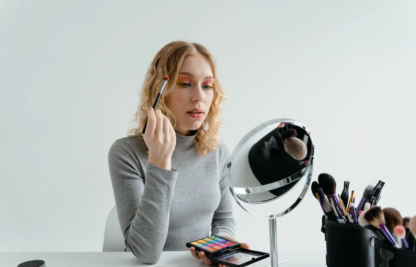 Blond woman putting on eyeshadow. - must have eye makeup brushes