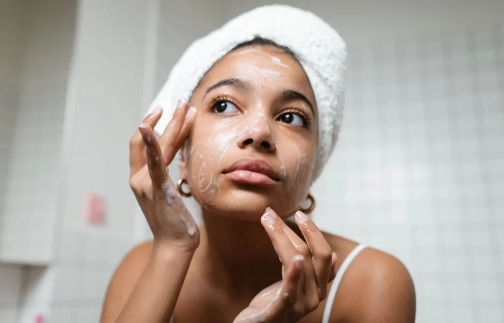 Woman in white tank top washing her face with soap. - Cerave Skincare Routine For Acne