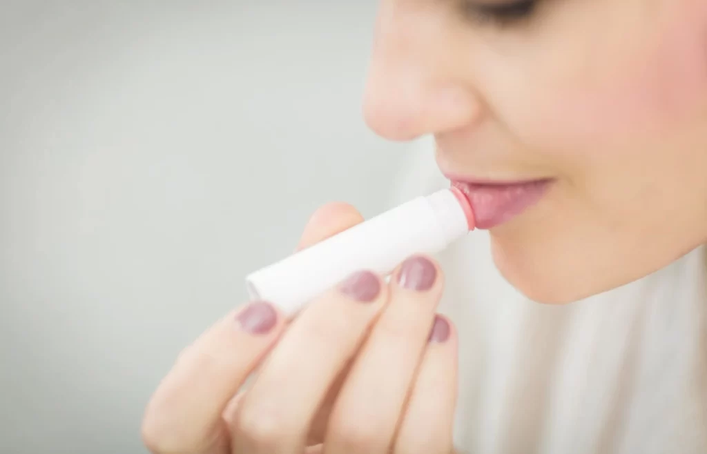 Woman applying a lip balm -Top 10 Skin Care Tips For Summer