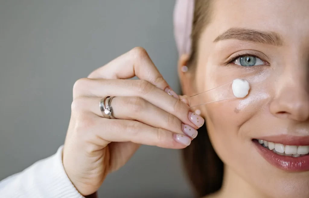 A woman applying cream to her face - Moisturizers For Combination Skin