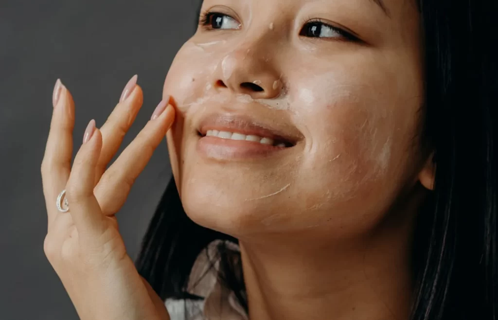 A woman applying a cream on her face - Fall Skin Care Tips