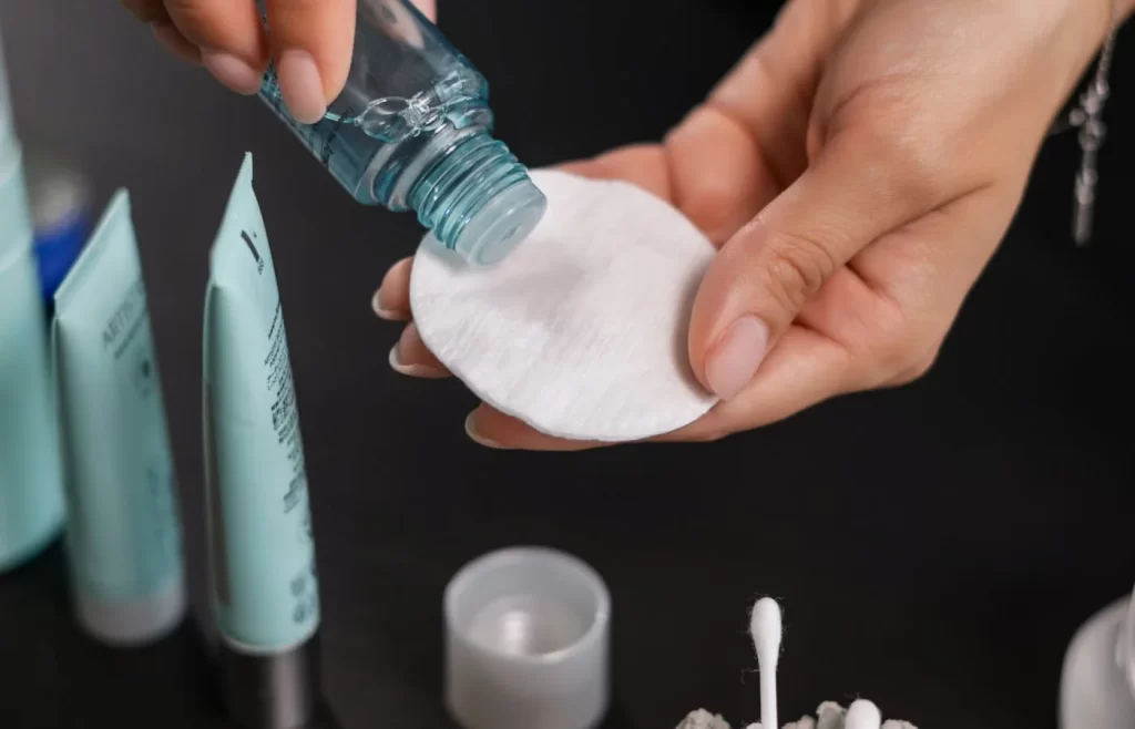 A person pouring toner on a cotton - Best Toners For Acne Prone Skin