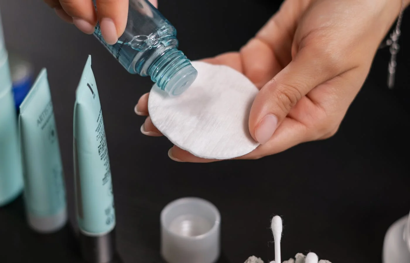 A person pouring toner on a cotton - Best Toners For Acne Prone Skin