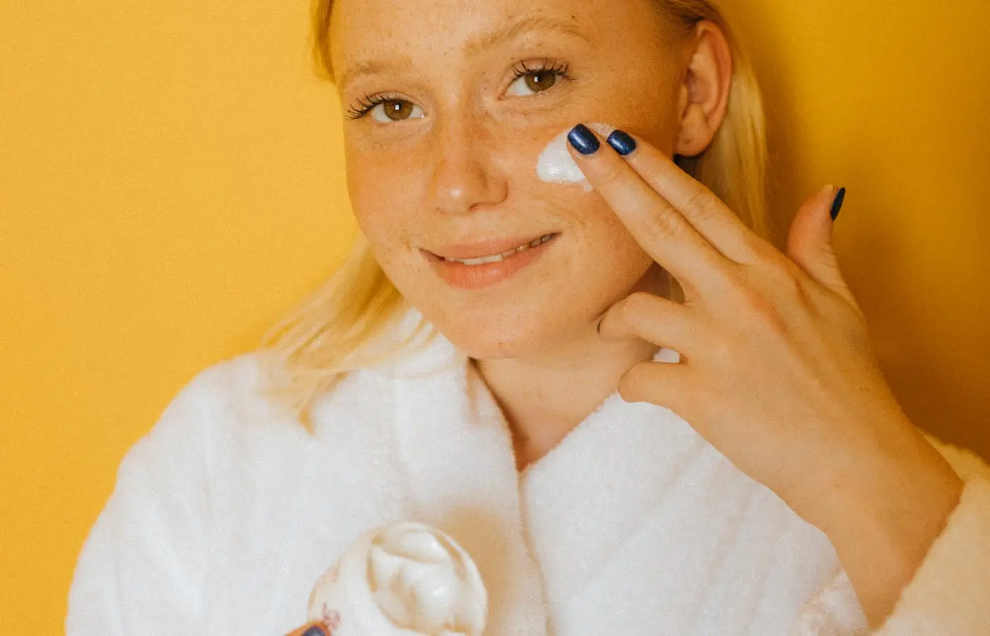 Woman applying cream on her face - Moisturizers To Use With Retinol