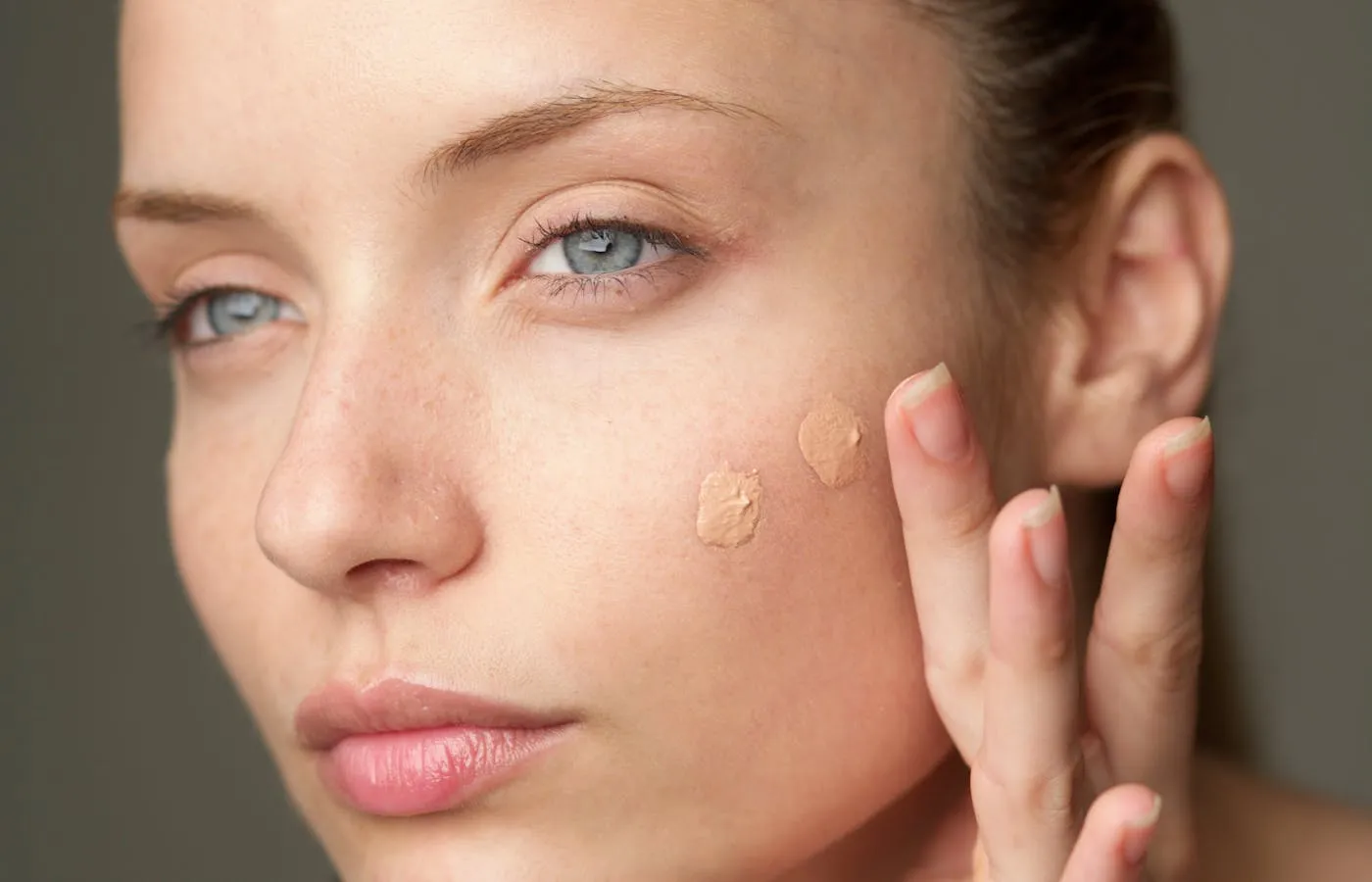 Woman applying foundation with fingers - Best Tinted Sunscreens