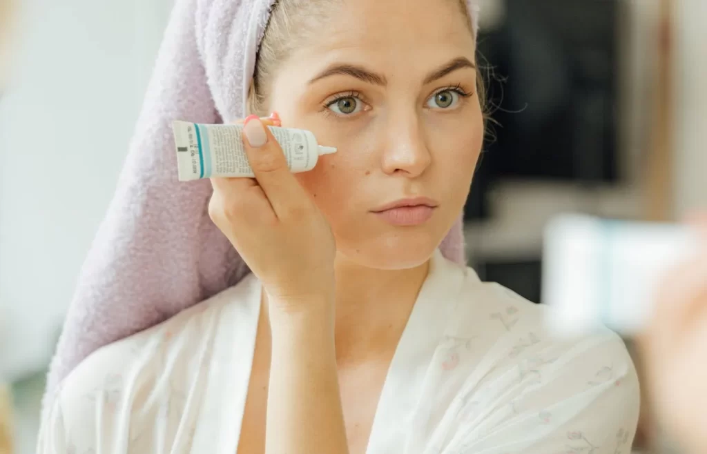 Woman applying cream on face - How to apply makeup on dry skin