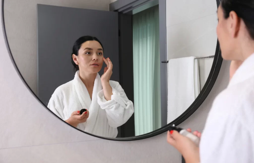 Woman in a white robe applying skincare - How To Start a Skincare Routine For Beginners