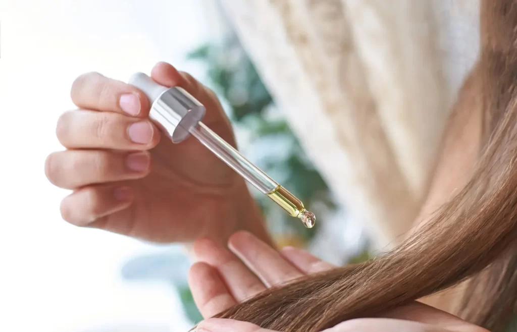 close up of someone applying oil on hair -hair care routine for low porosity hair